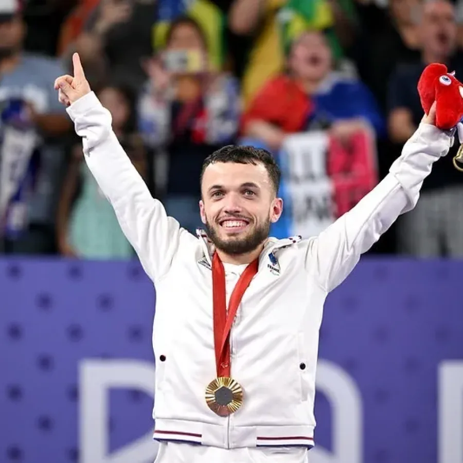 Charles Noakes, médaille autour du cou, bras levés vers le public