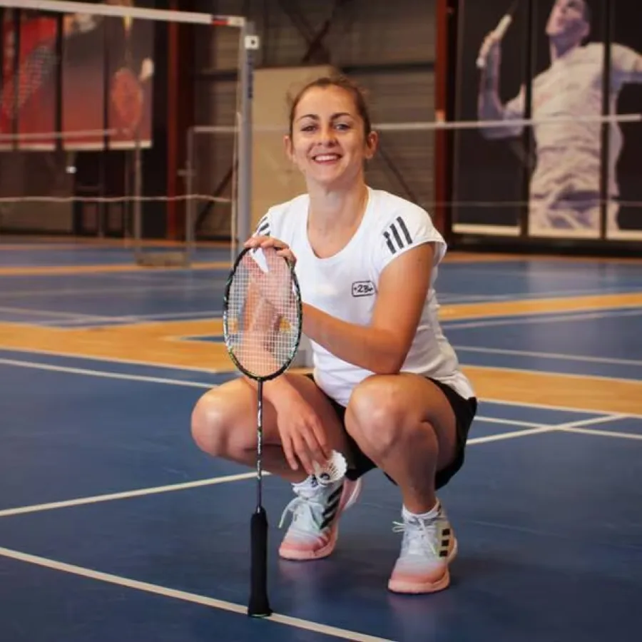 Faustine Noël, accroupie raquette en main sur un terrain de badminton